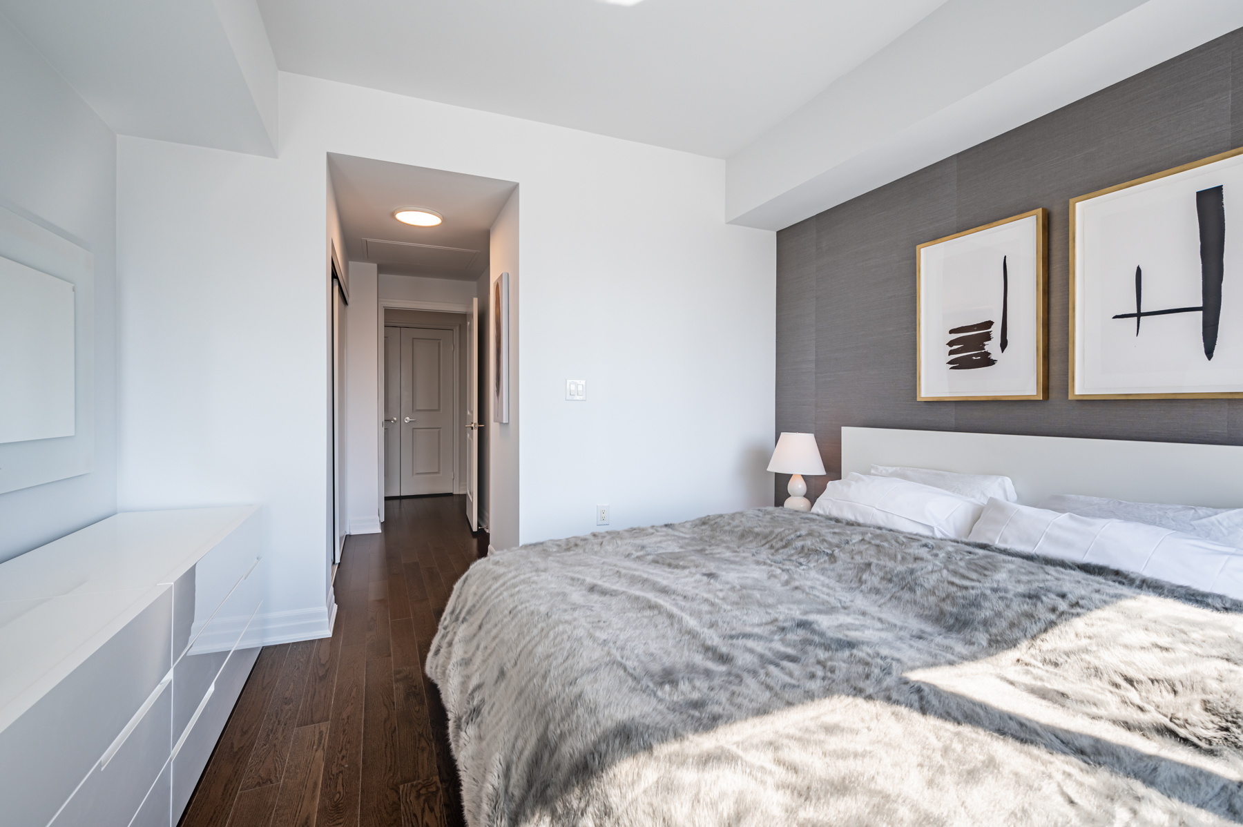 Condo bedroom with dark back wall hung with art.