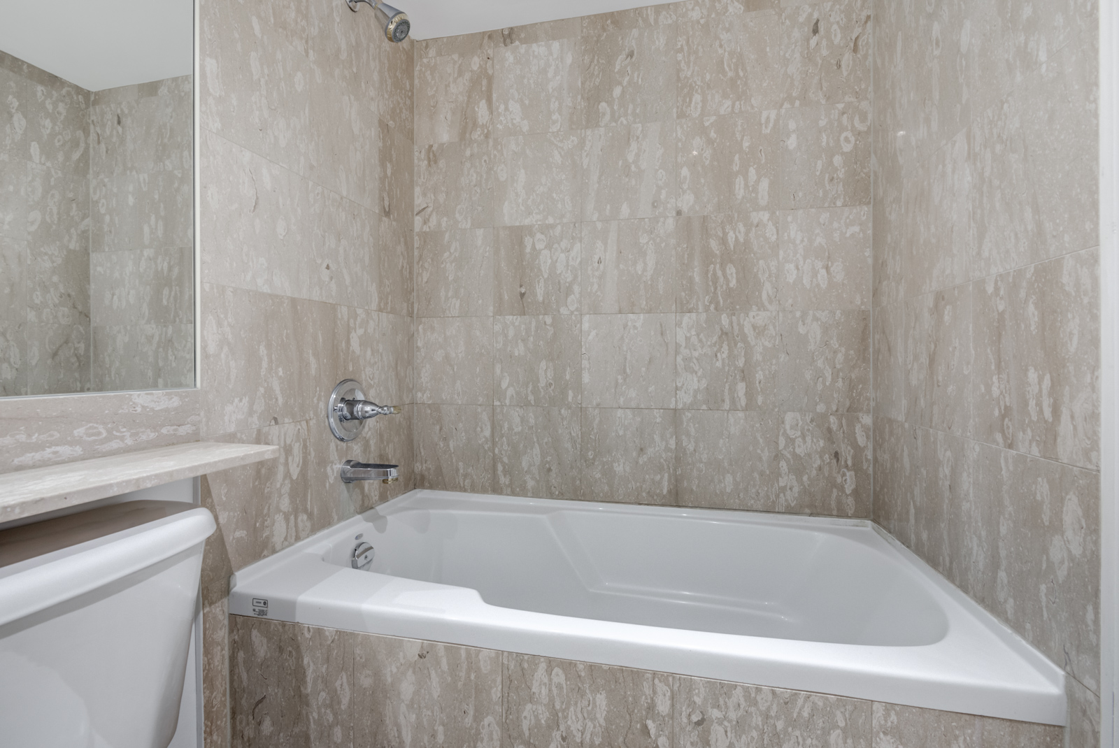 Closeup of 140 Simcoe St E Unit 921 soaker tub with tiles and white trim.