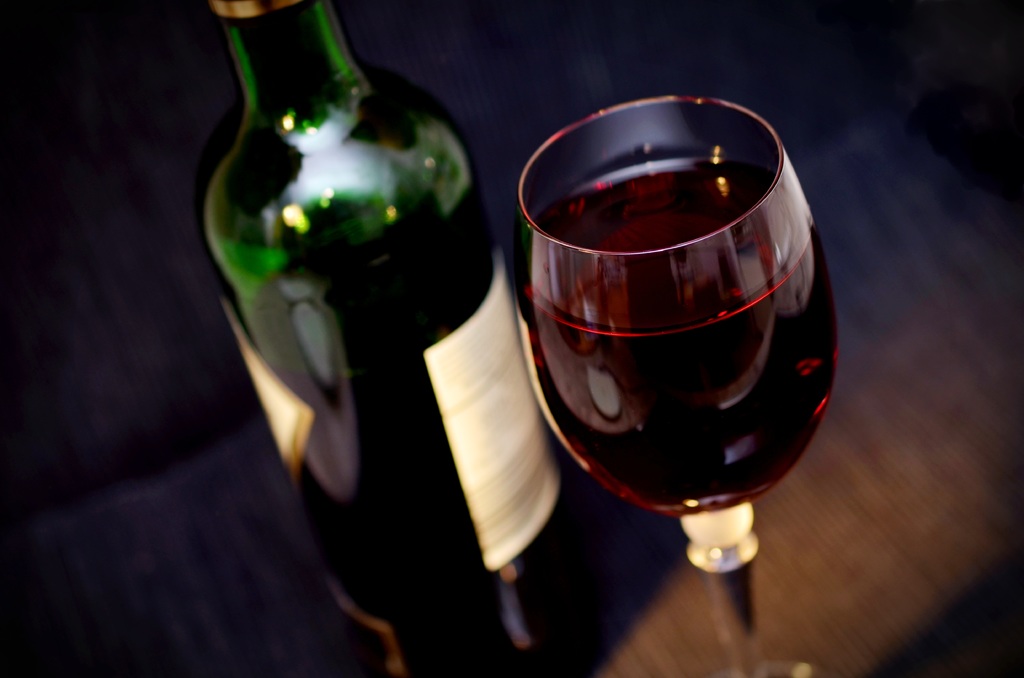 Close up of red wine in wine glass and green bottle. 