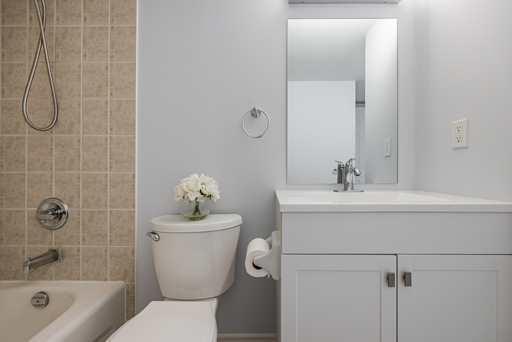 Bathroom with built-in vanity, cupboards and tall mirror.