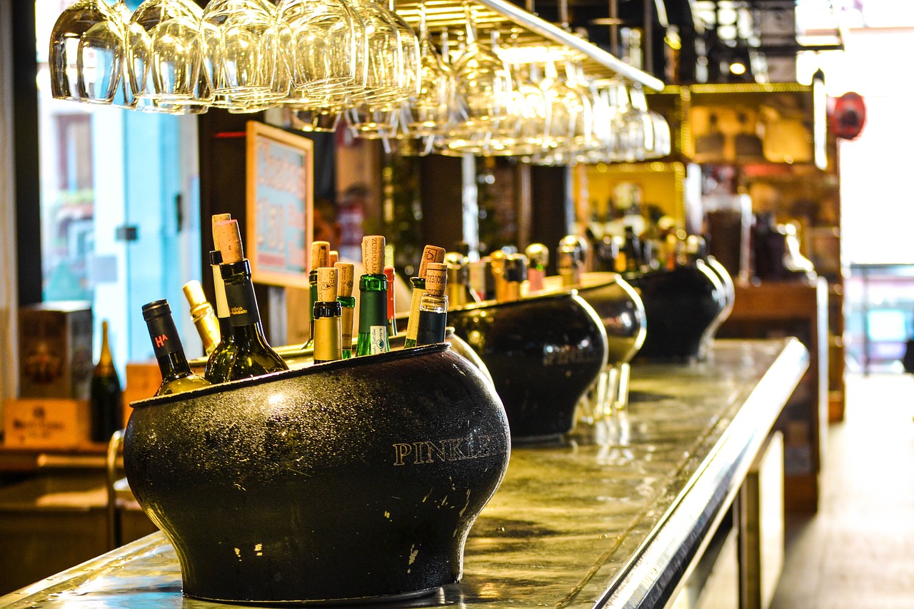 Wine bottles in ice black ice buckets and hanging wine glasses in a bar.