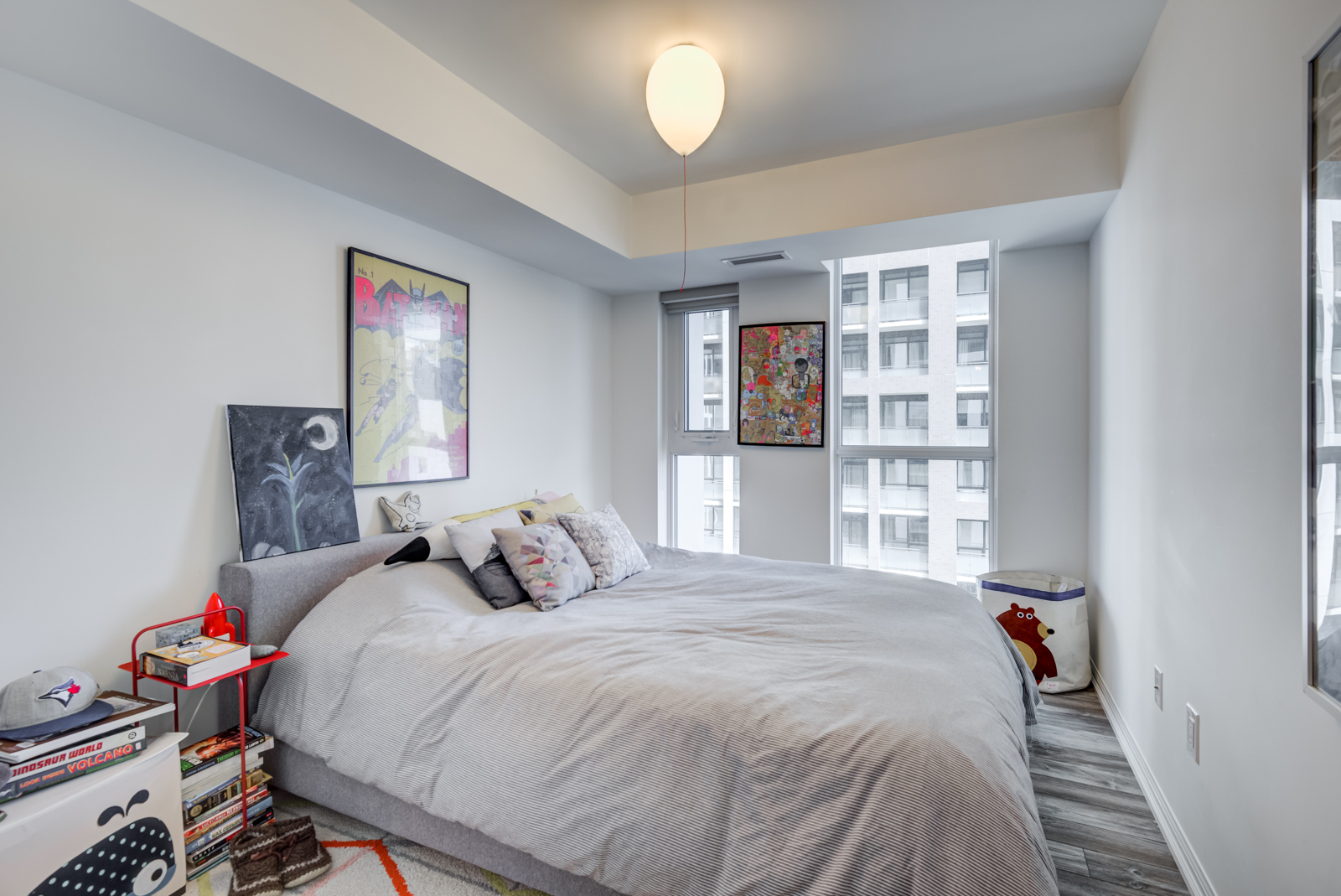 Second bedroom with large bed and windows plus wall art.