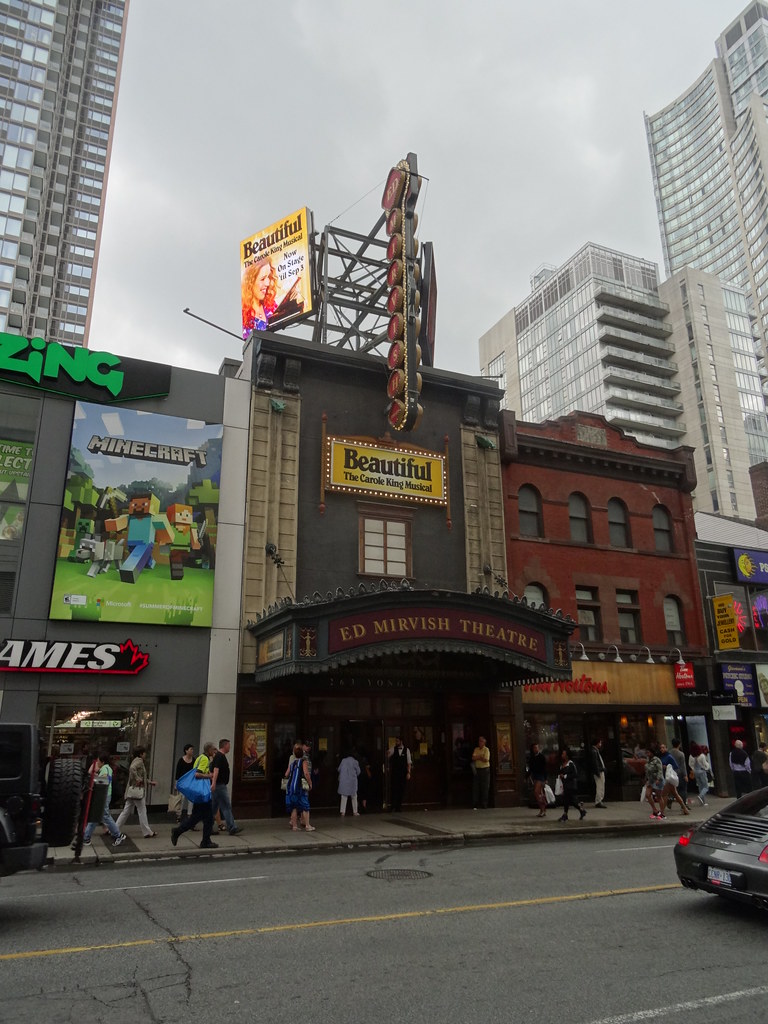 Exterior of Ed Mirvish Theatre on Victoria St in Toronto with pedestrians and billboards.