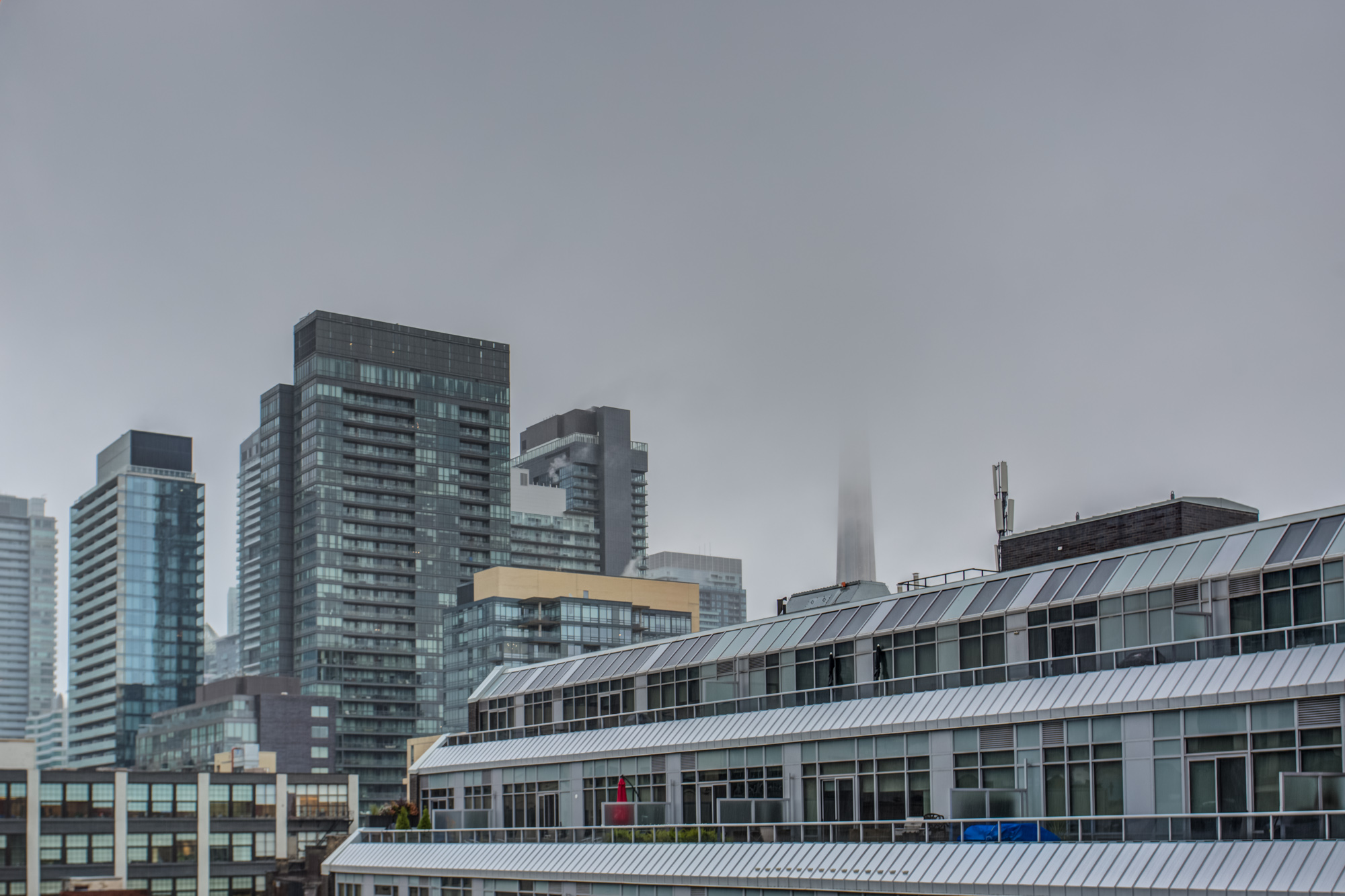 View of fog-covered CN Tower and Toronto buildings from balcony of 39 Brant St Unit 918, Brant Park Lofts.