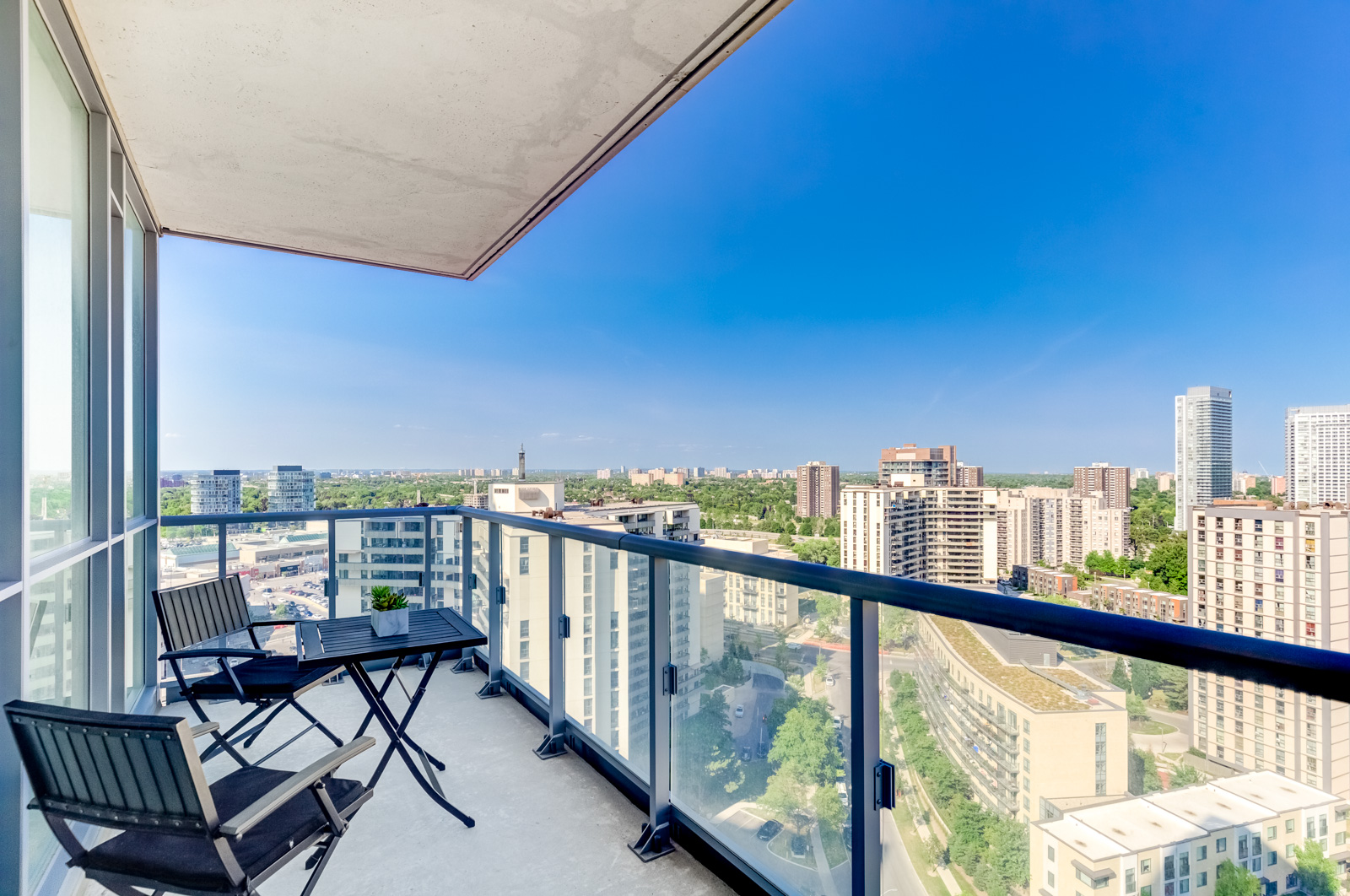 Glass paneled balcony with coffee table and chairs and view of North York, Toronto.