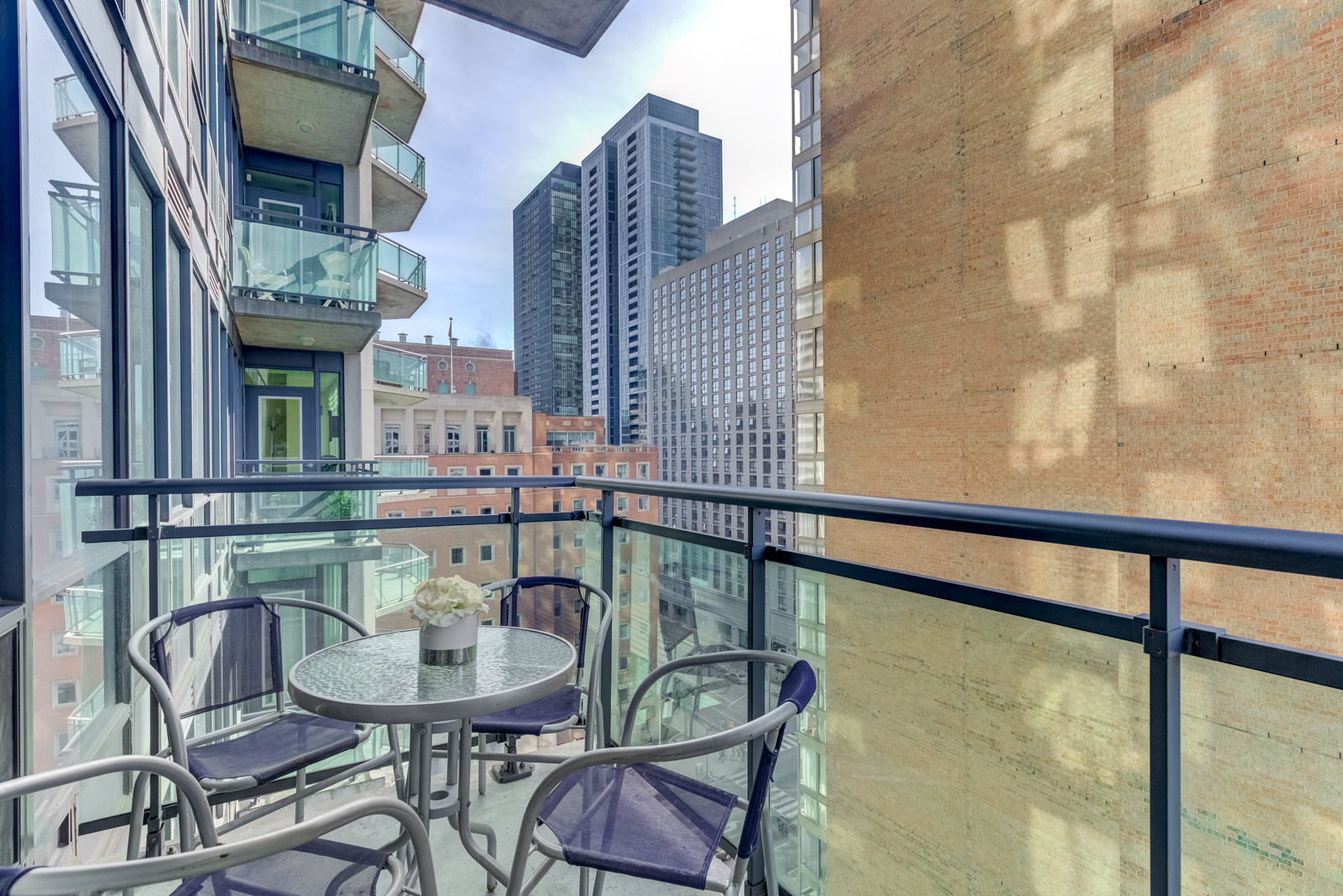 300 Bloor St E Unit 1809 balcony with round table surrounded by 4 chairs overlooking buildings along Rosedale Valley.