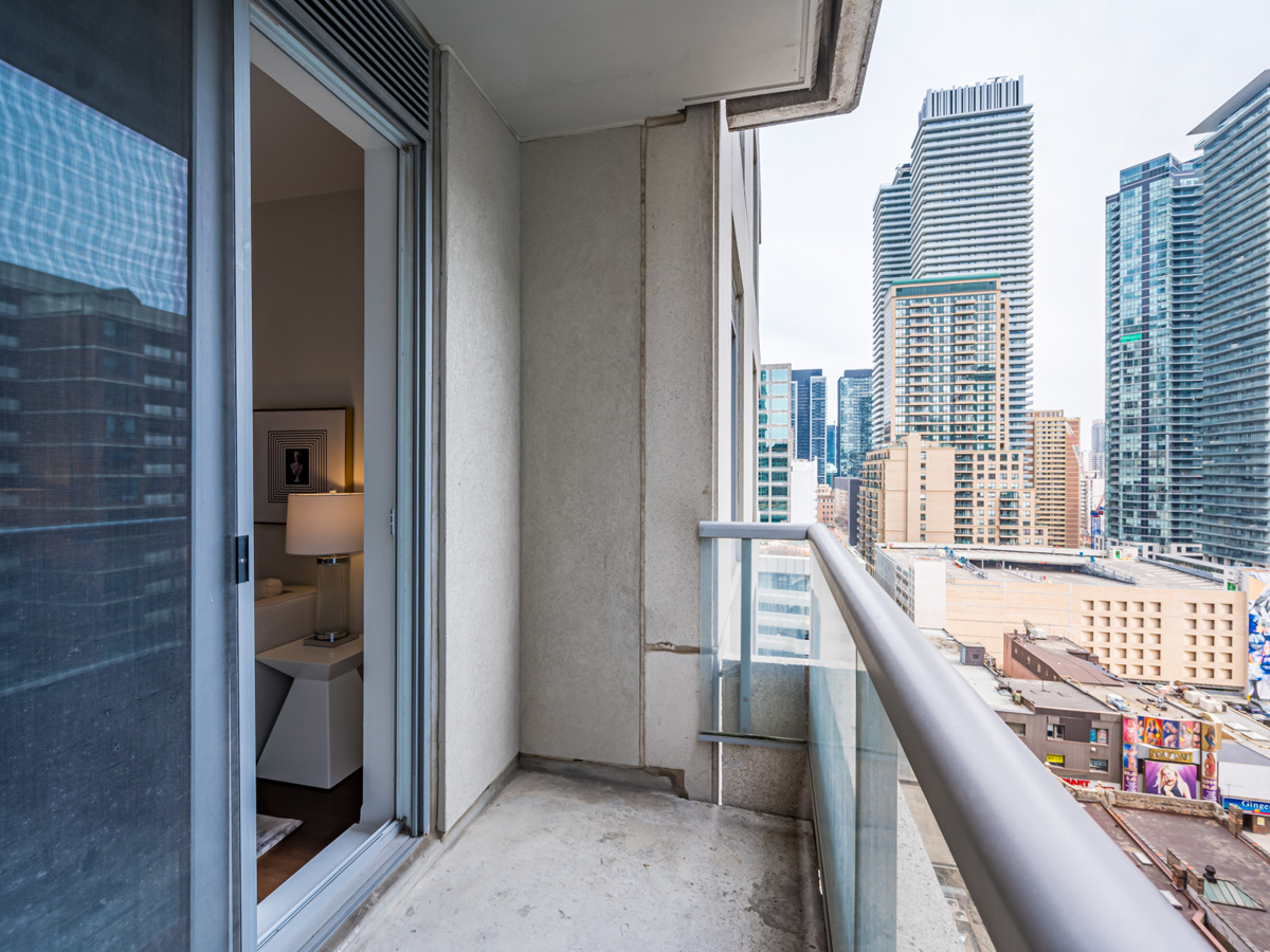 Condo balcony with glass panels and concrete floor.