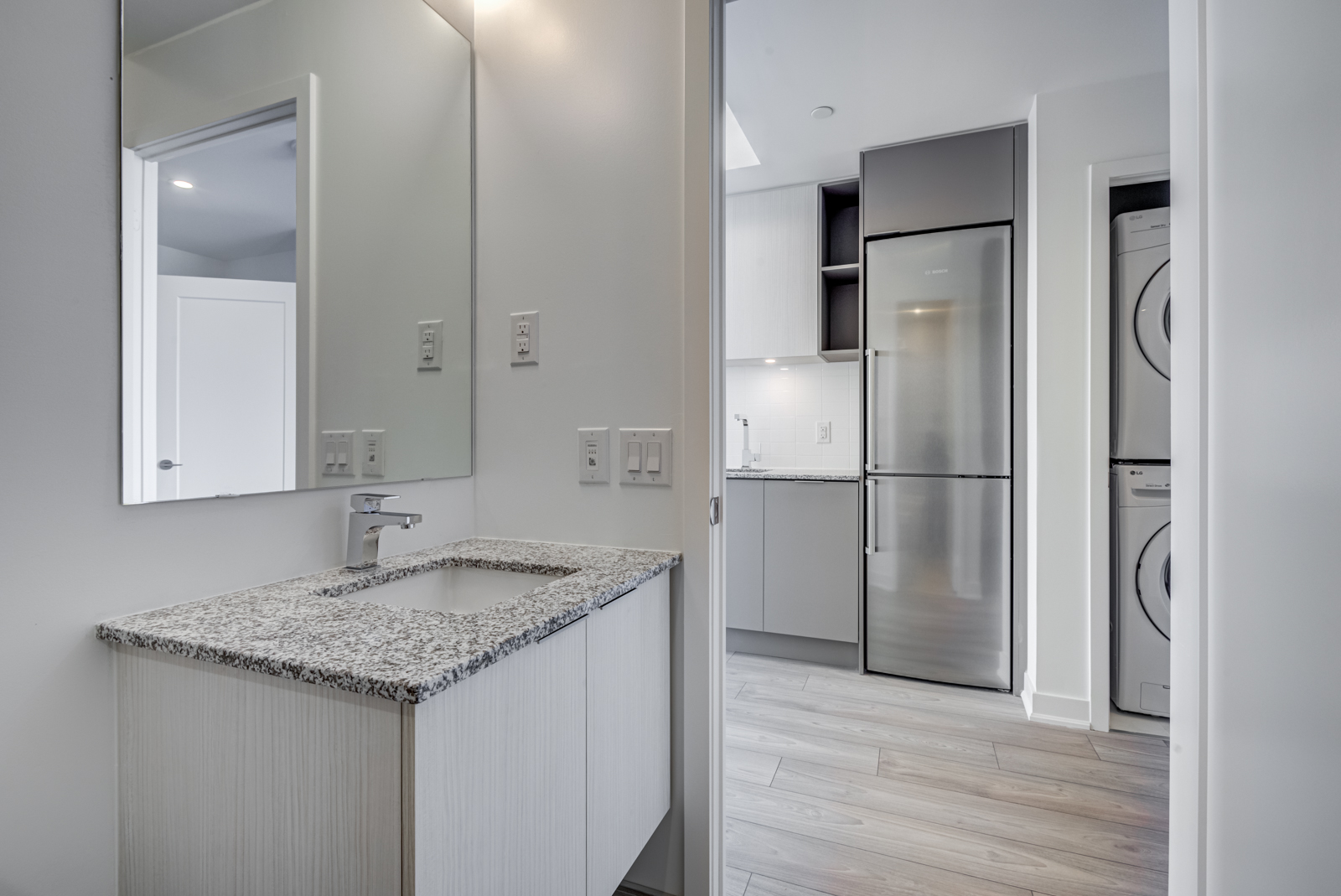 Condo bathroom with speckled counter-top and large vanity.