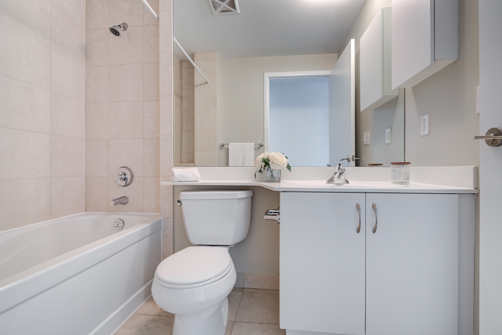 215 Fort York Blvd ensuite bath with white toilet, tub, sink, cabinets and huge mirror.