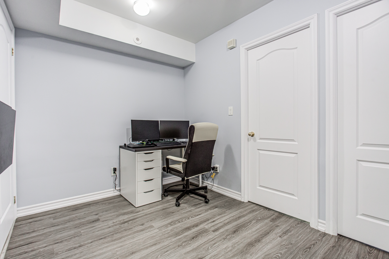 Home office with desk, chair with wheels, 2 computer monitors, and gray filing cabinet.