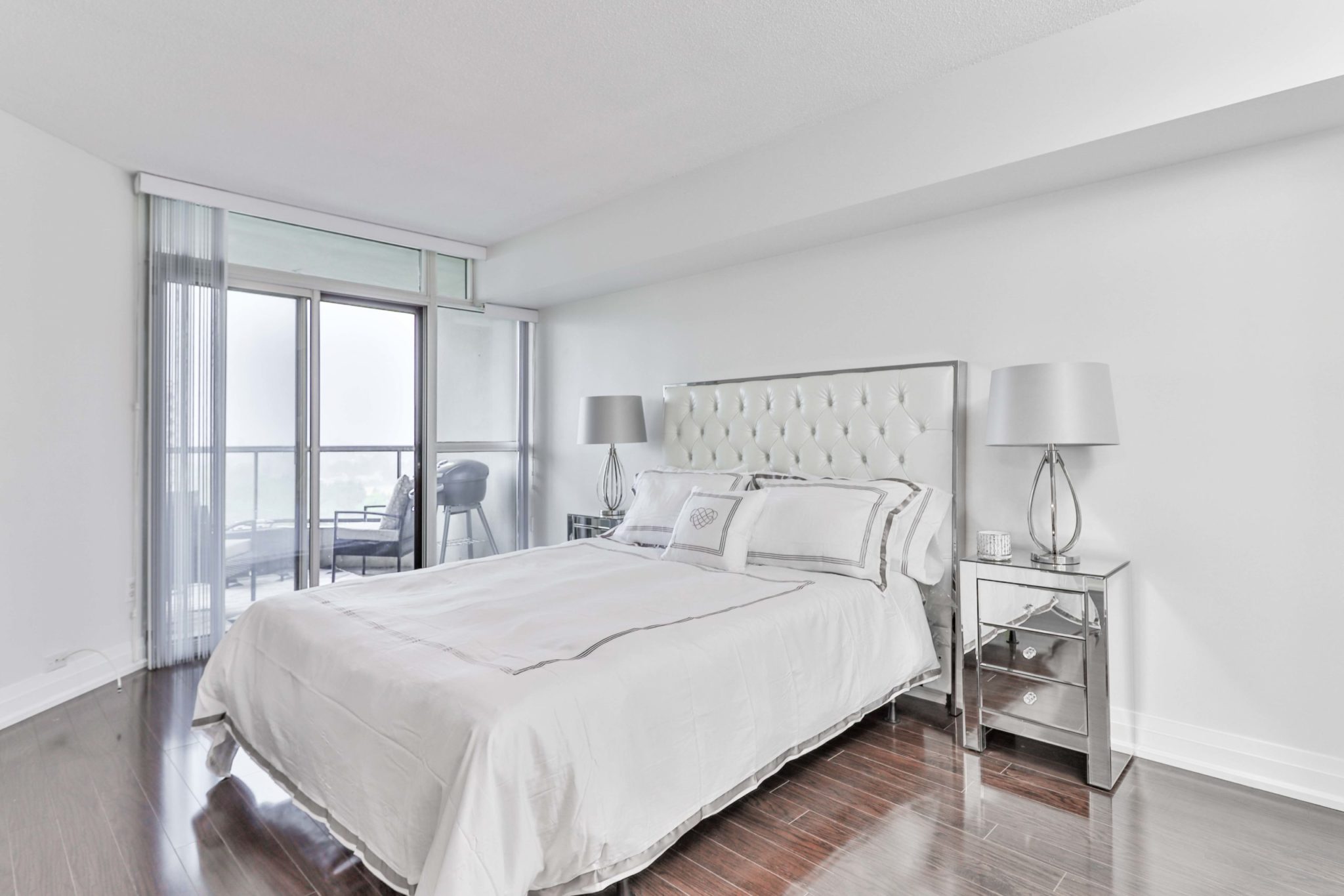 Master bedroom with walk-out balcony and shiny laminate floors.