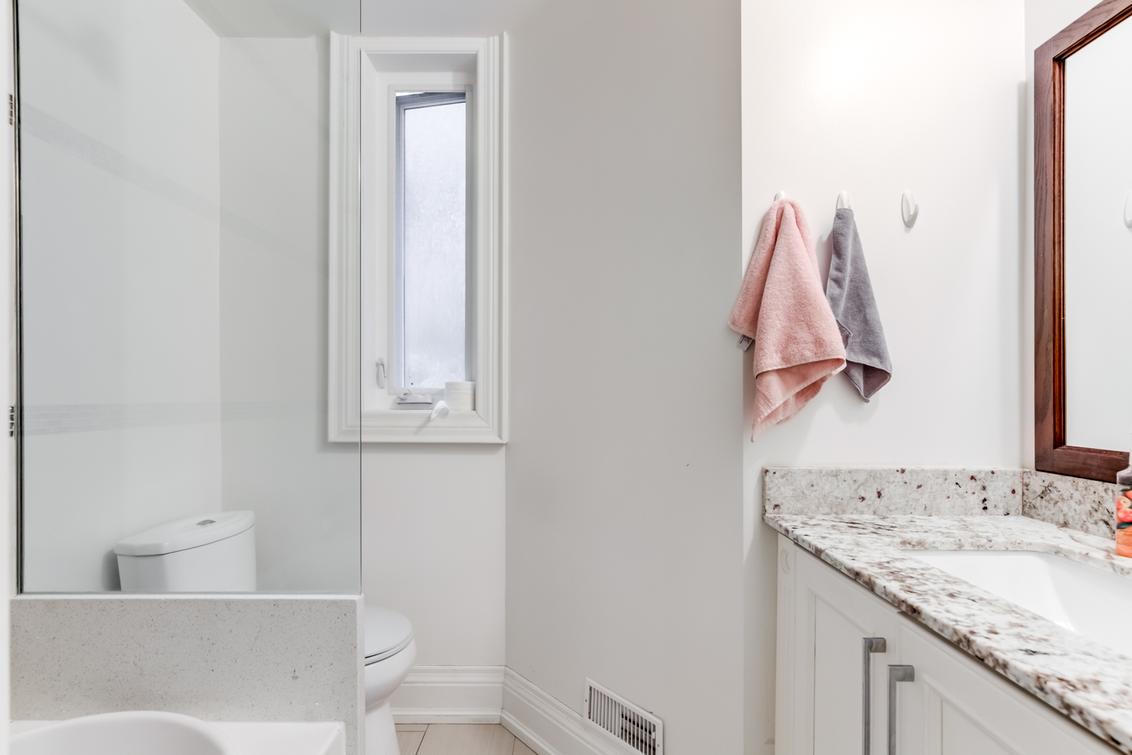 Simple kitchen with gray walls, marble counters and white toilet.