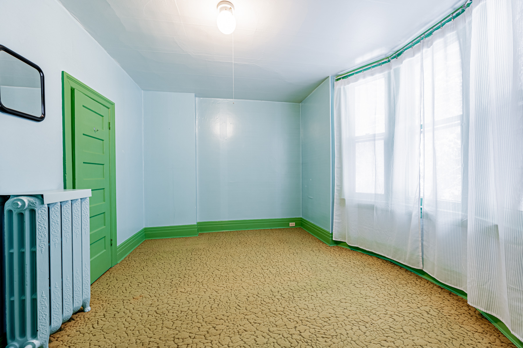 Spacious bedroom with unfinished floors, blue walls and large windows.