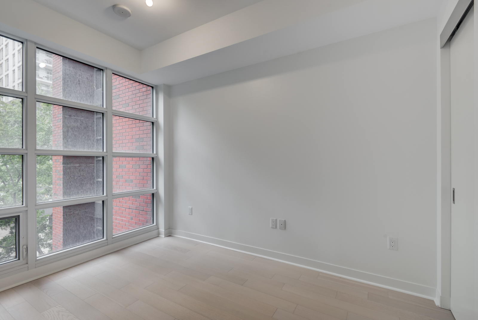 Close up of master bedroom windows showing red-brick building and tree.