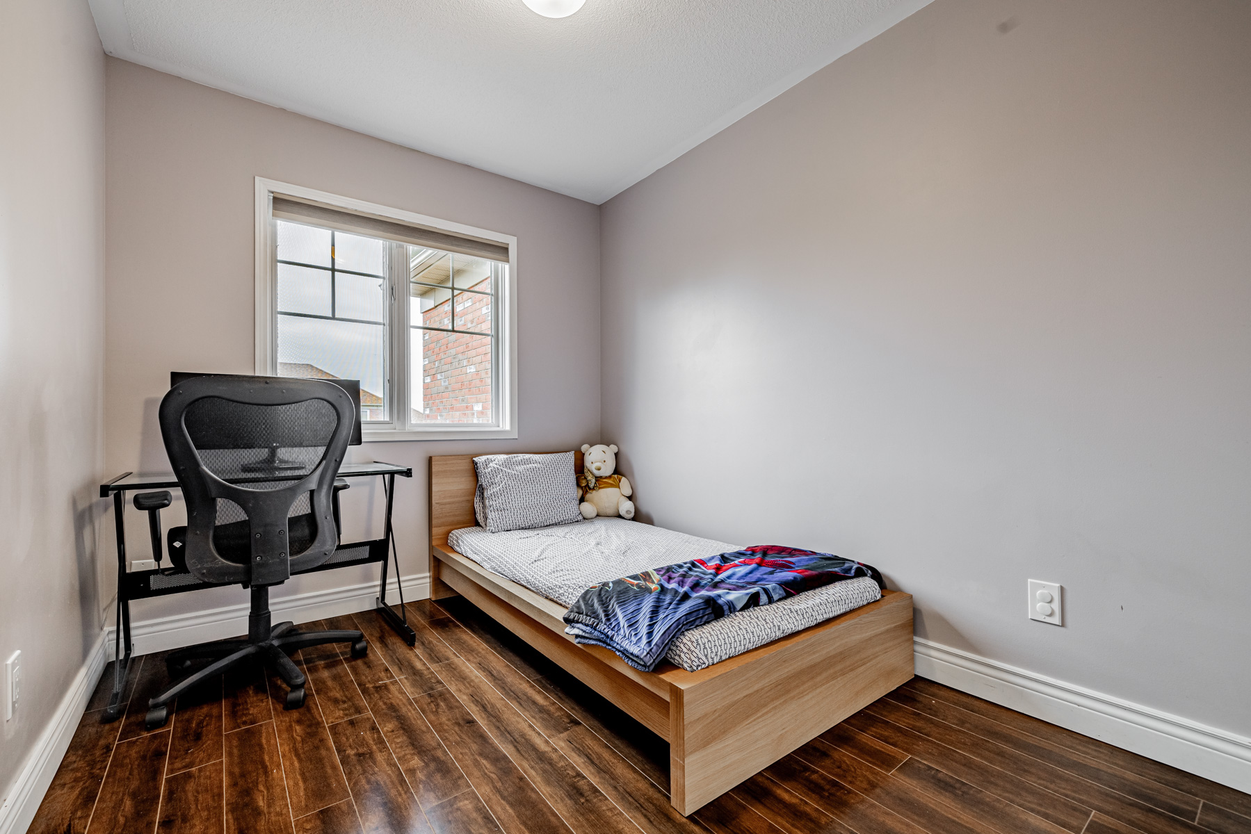 77 Schouten Cres 2nd bedroom with desk, chair, bed and dark laminate floors.