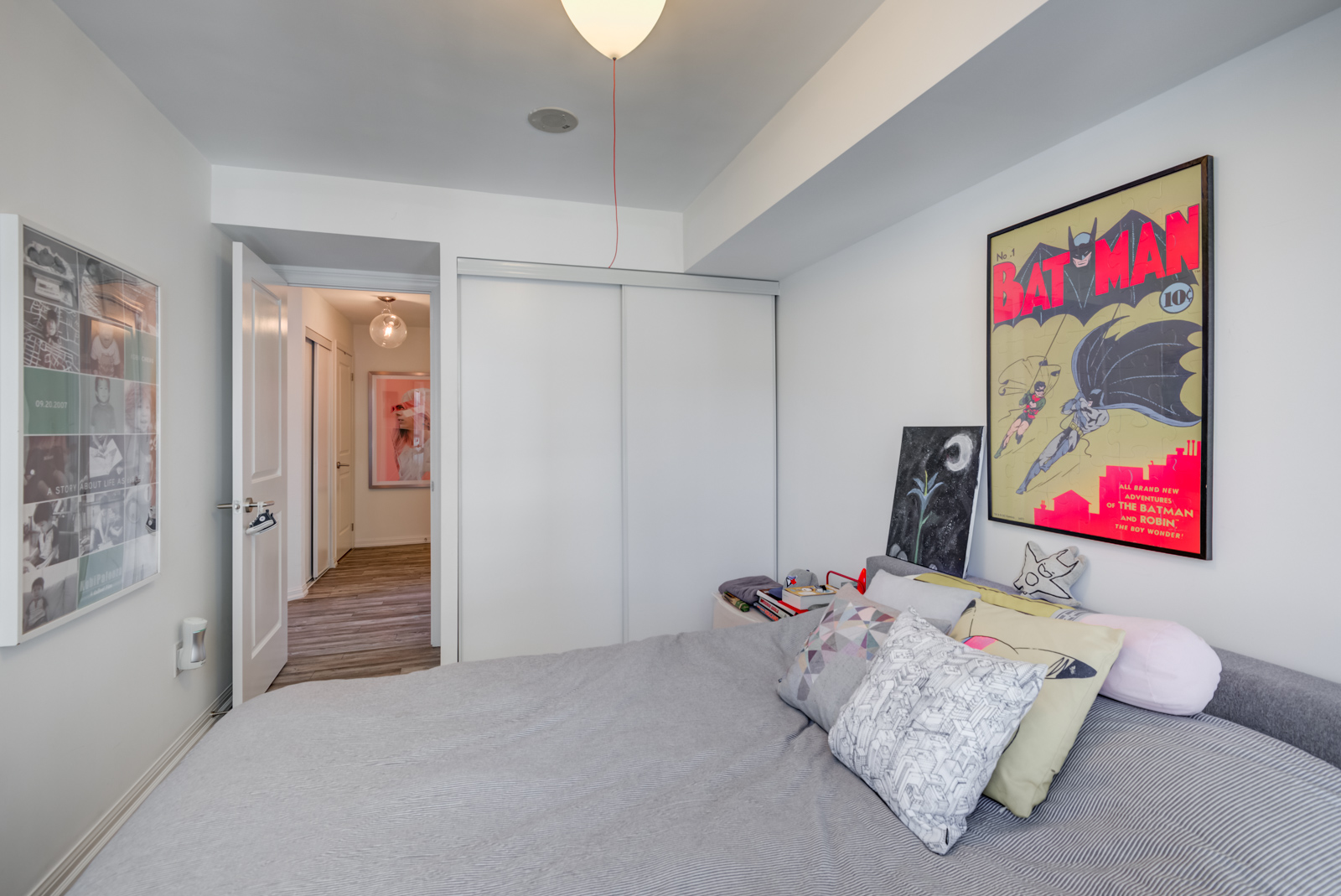 View of closed closet, bed and classic Batman and Robin poster.