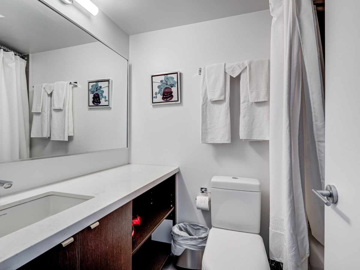 Toronto condo bathroom with simple gray colours, white counters and large vanity.