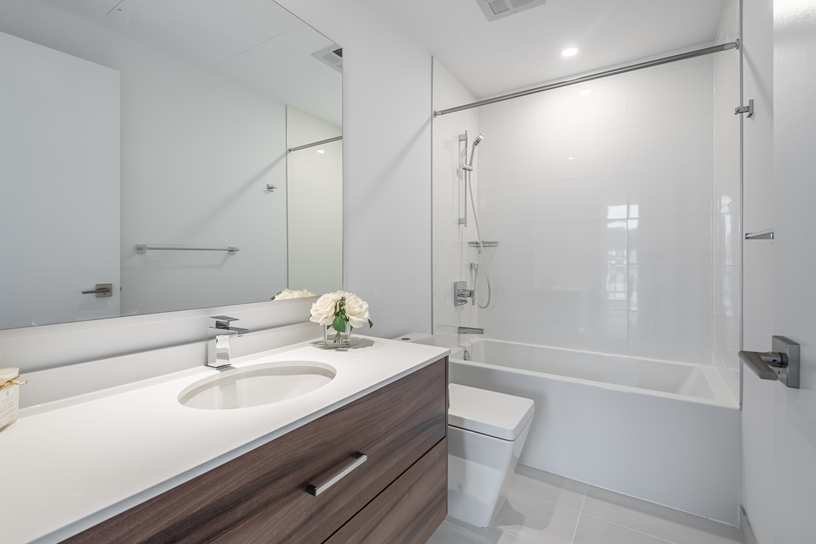 Bathroom with glistening white tiles, gray walls, soaker tub and large vanity.