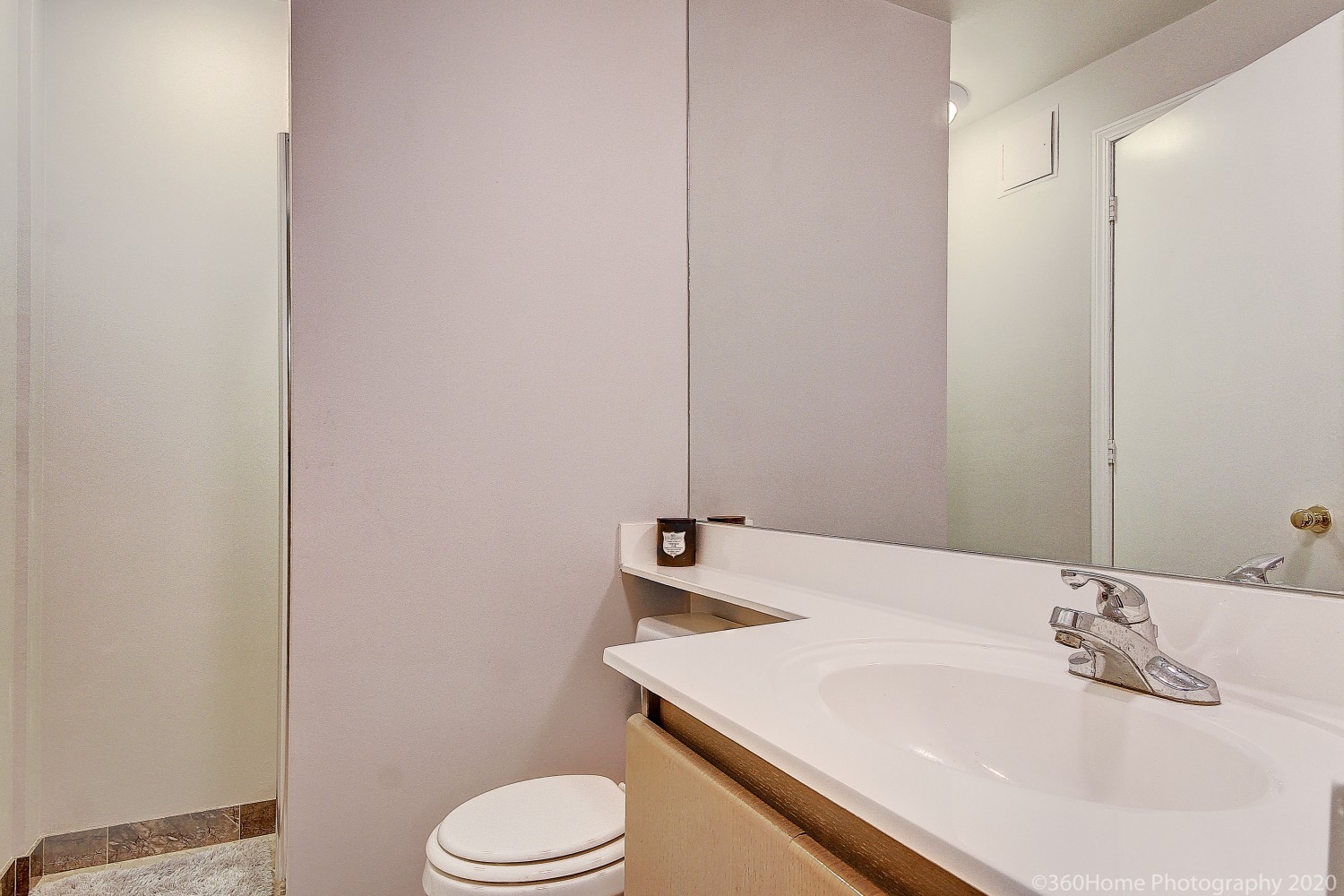 Close up of washroom sink with white counter-top and large vanity.