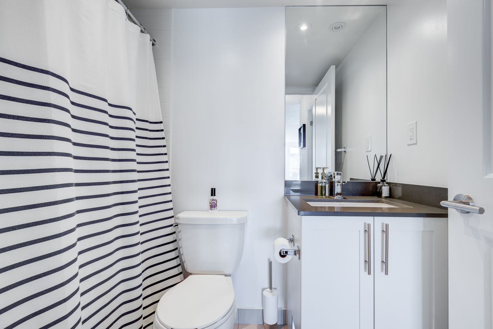 Bathroom in monochromes, striped shower curtain and sleek vanity.