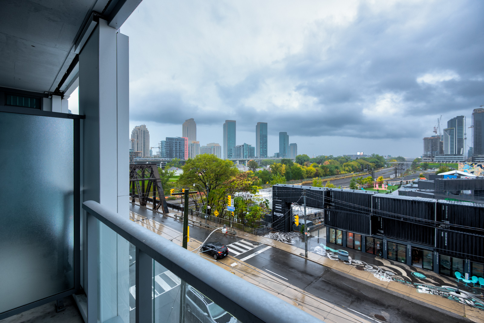 Balcony view from Minto Condos of distant buildings, cloudy skies and slippery, rain-soaked Bathurst St.
