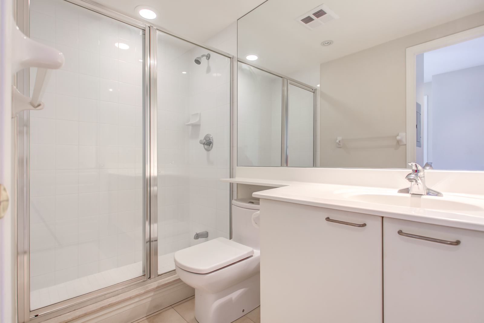 Washroom of 20 Collier St Unit 408 with walk-in shower, white sink and cabinet, and huge mirror.