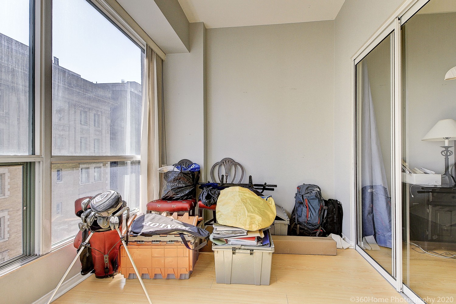 View of 817 - 7 King St E den with boxes, files, knapsacks and golf equipment on floor.