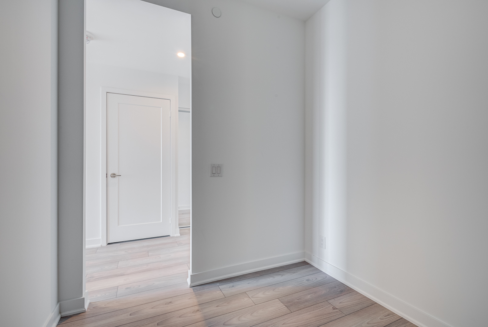 Empty condo den with laminate floors and gray walls.