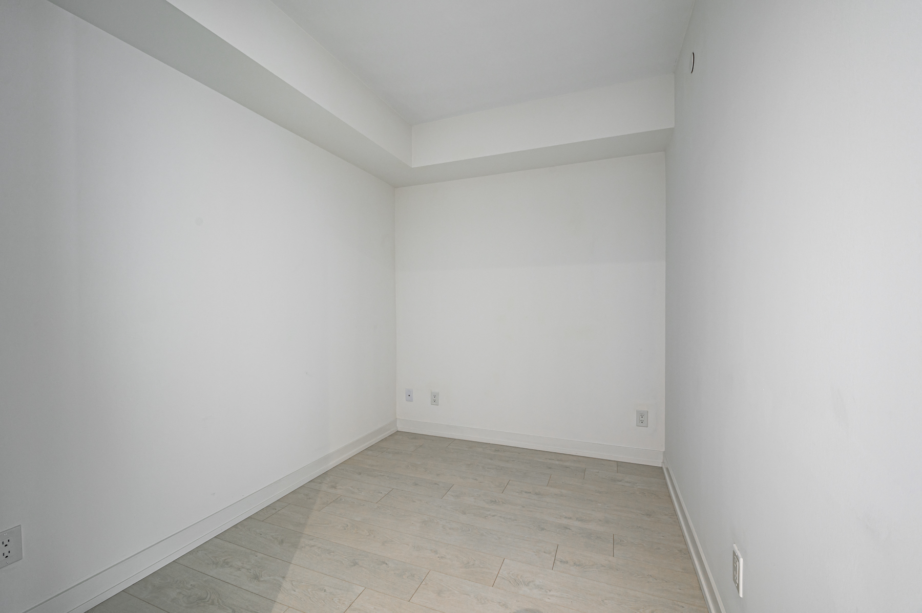 Empty condo den with gray walls and laminate floors.