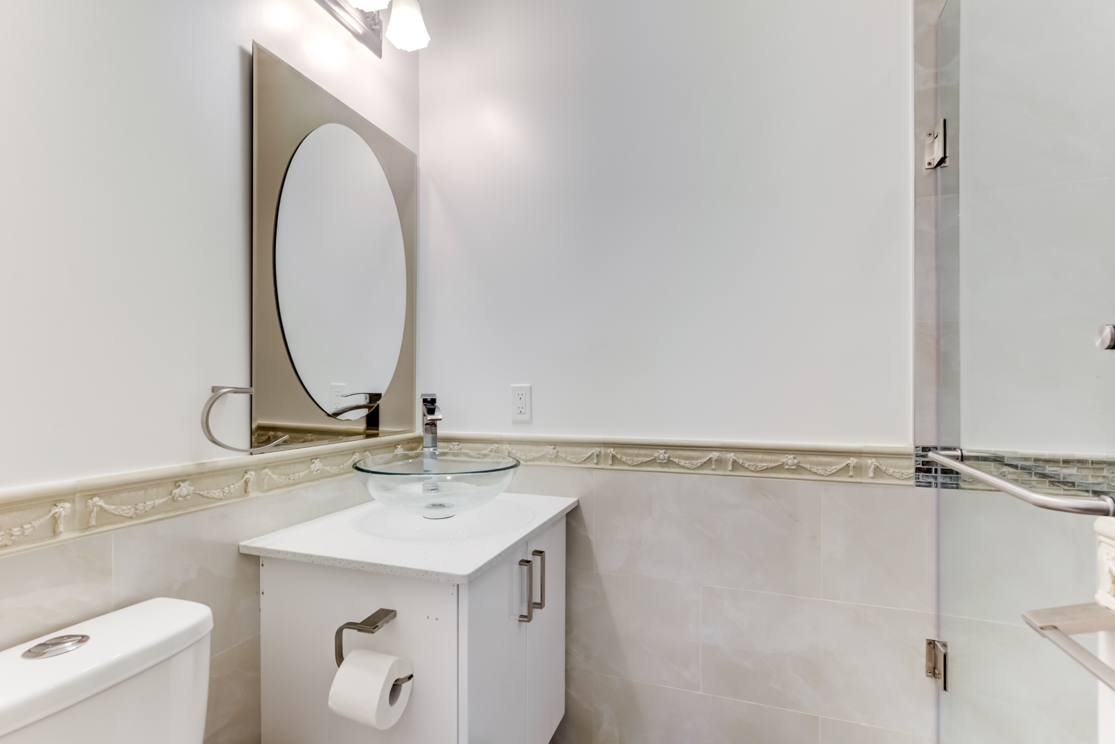 Renovated bathroom at 120 McGill St with white vanity, oval mirror and walk-in shower.