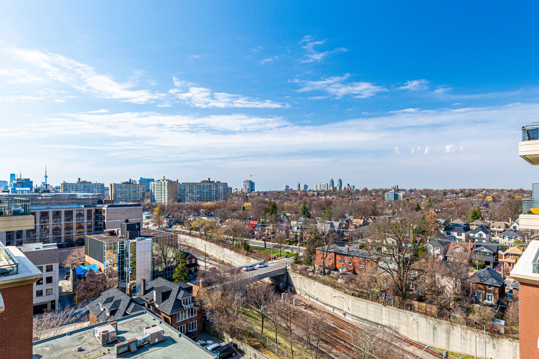 View of houses, buildings and trees of Midtown Toronto in foreground and downtown Toronto in background.