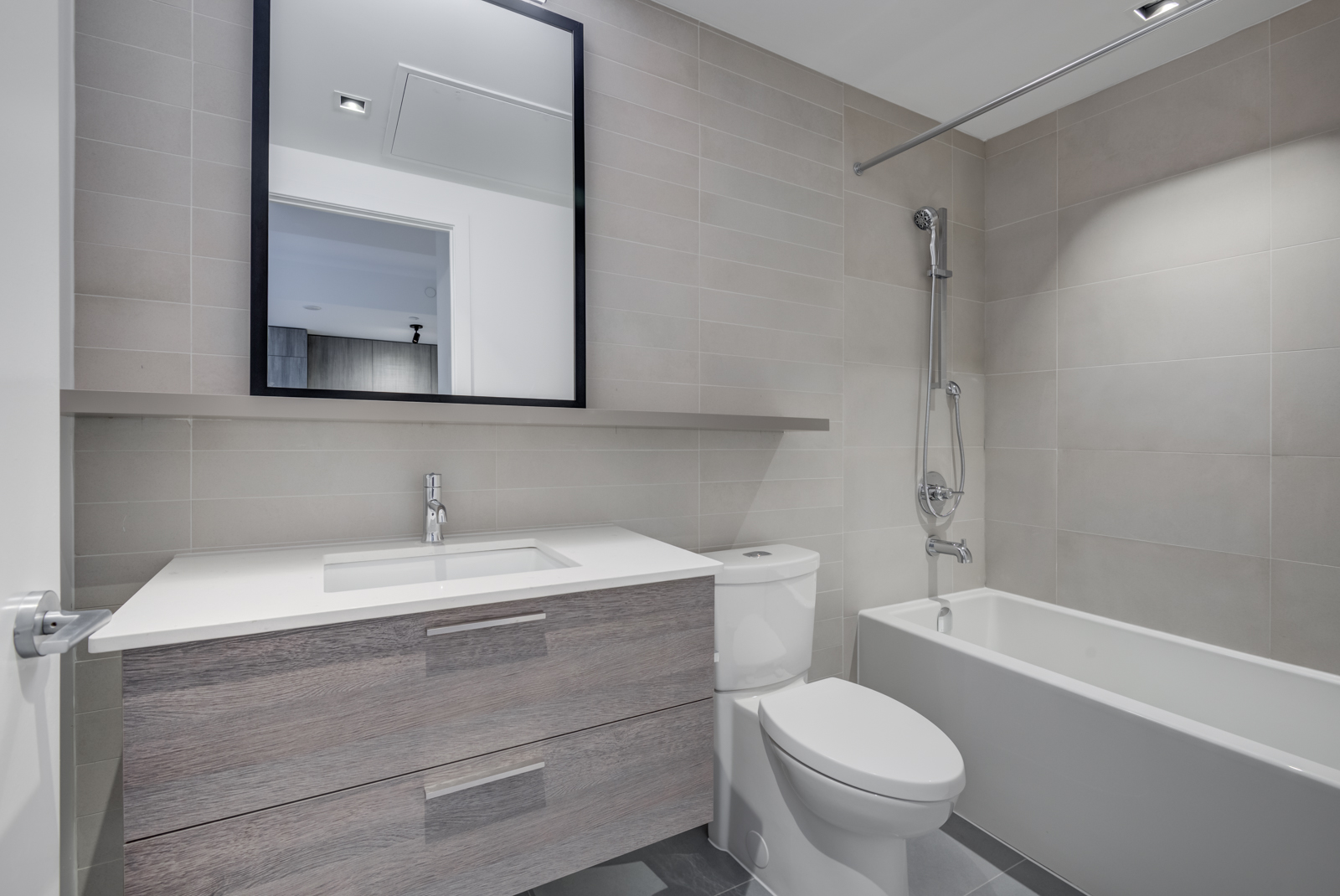 4-piece bathroom with white soaker tub, toilet, vanity, mirror and brown cabinets and tiles.