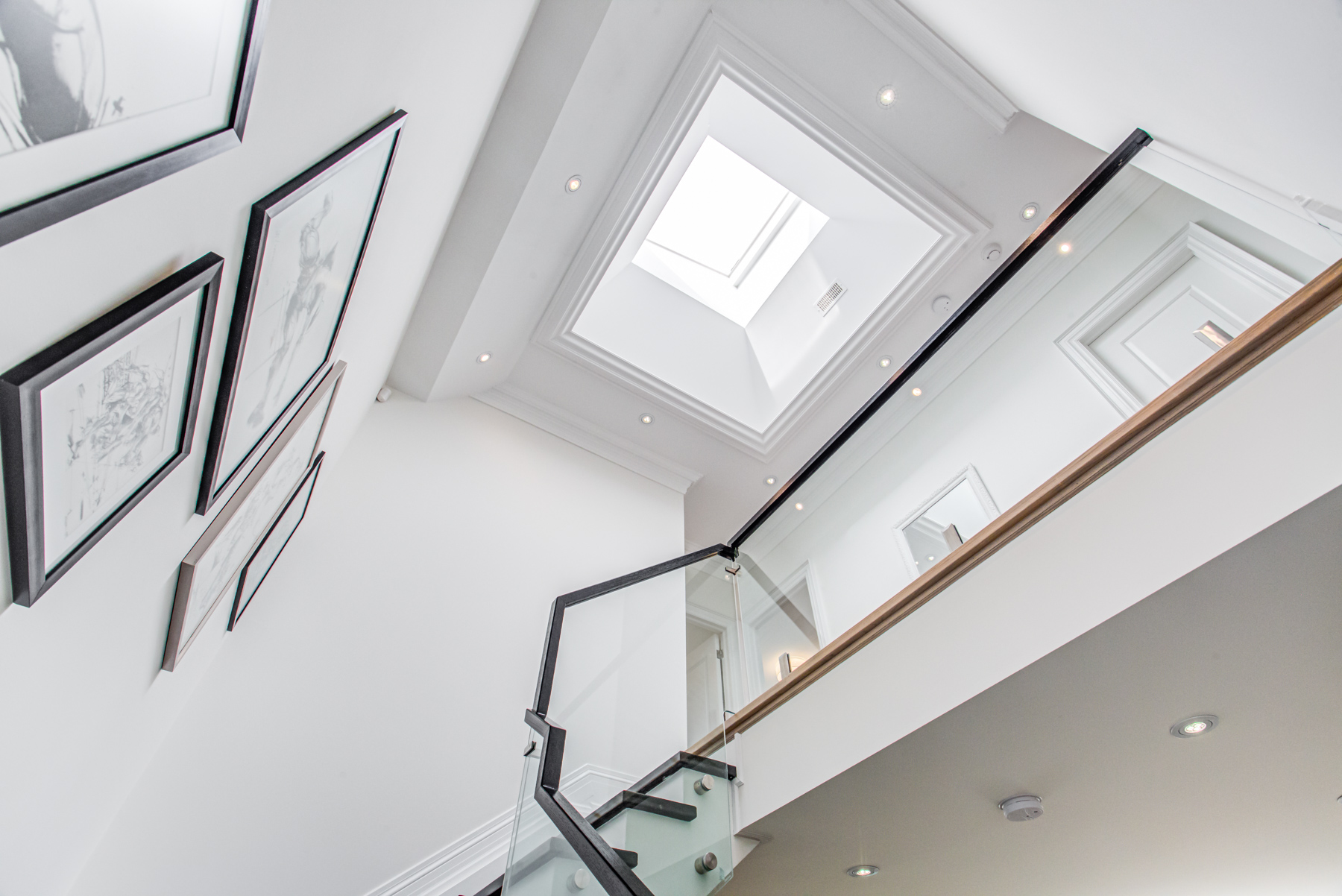 Staircase lit by pot-lights and a skylight.