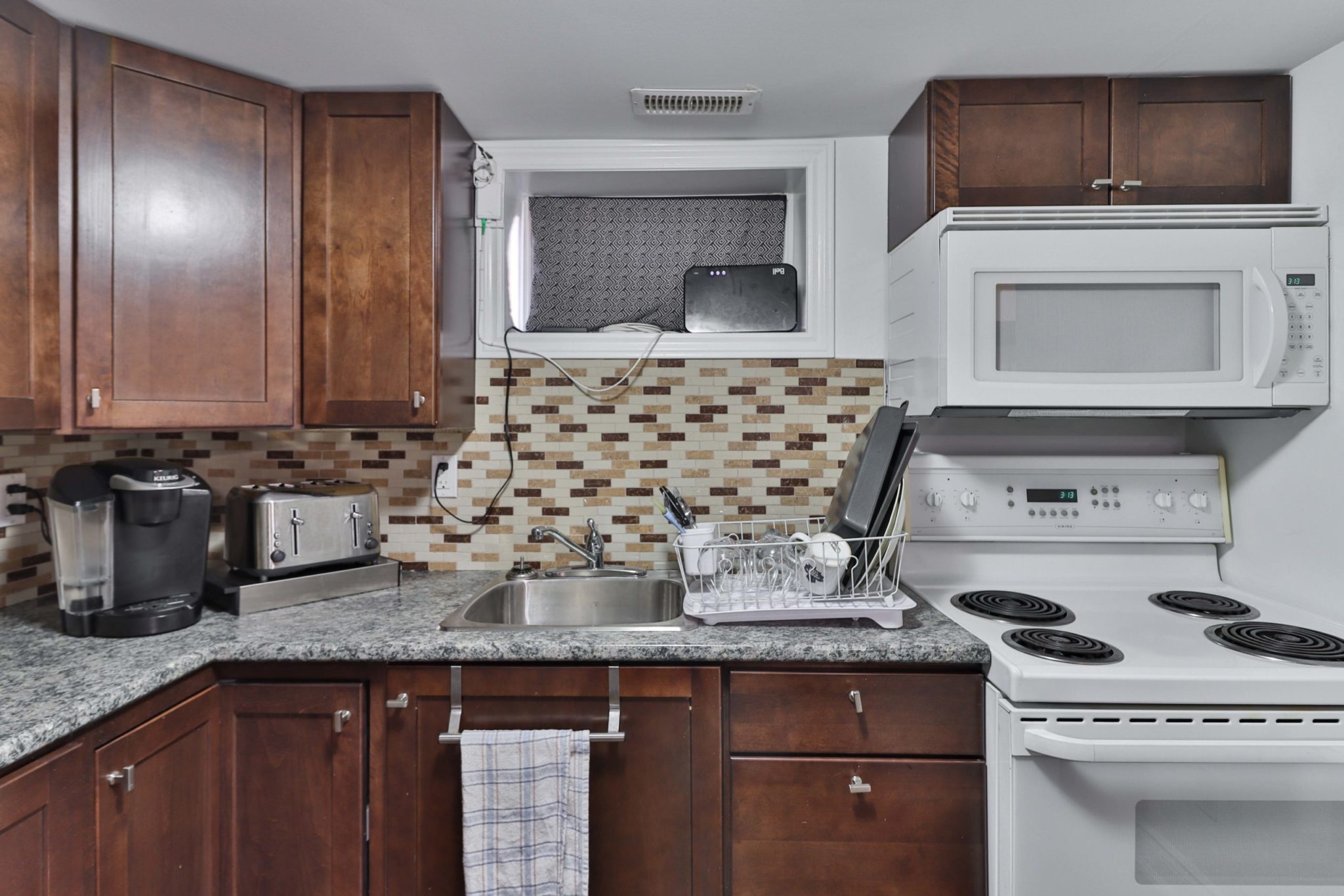 Basement kitchen with large white stove, microwave and tiled back-splash.