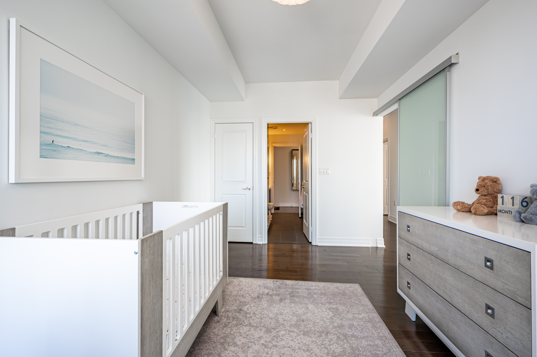 Condo bedroom with hardwood floors, dresser and closet.