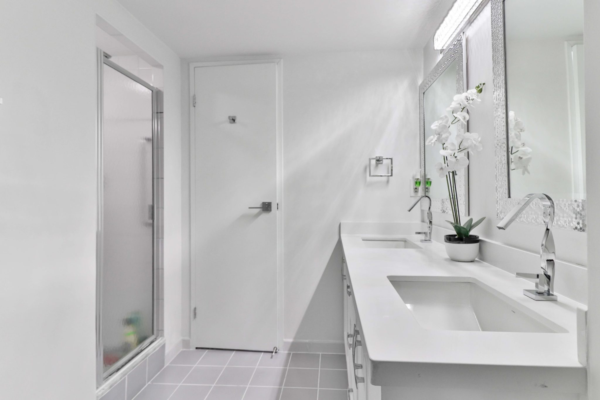 Ensuite bath with chic new faucets, double sinks, modern lighting and white quartz counter.