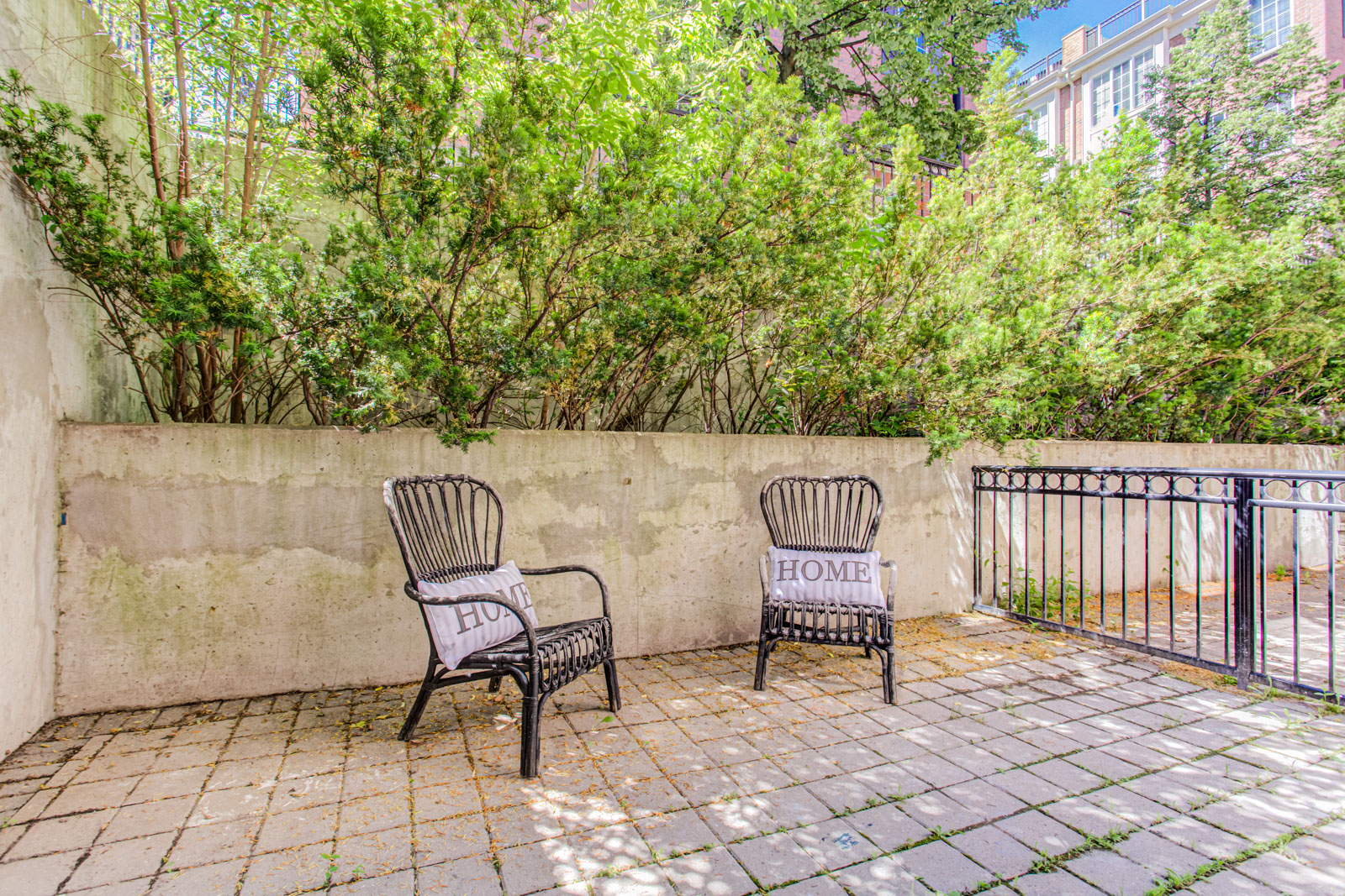 Large rear terrace with 2 metal chairs with white pillows that say “Home.”