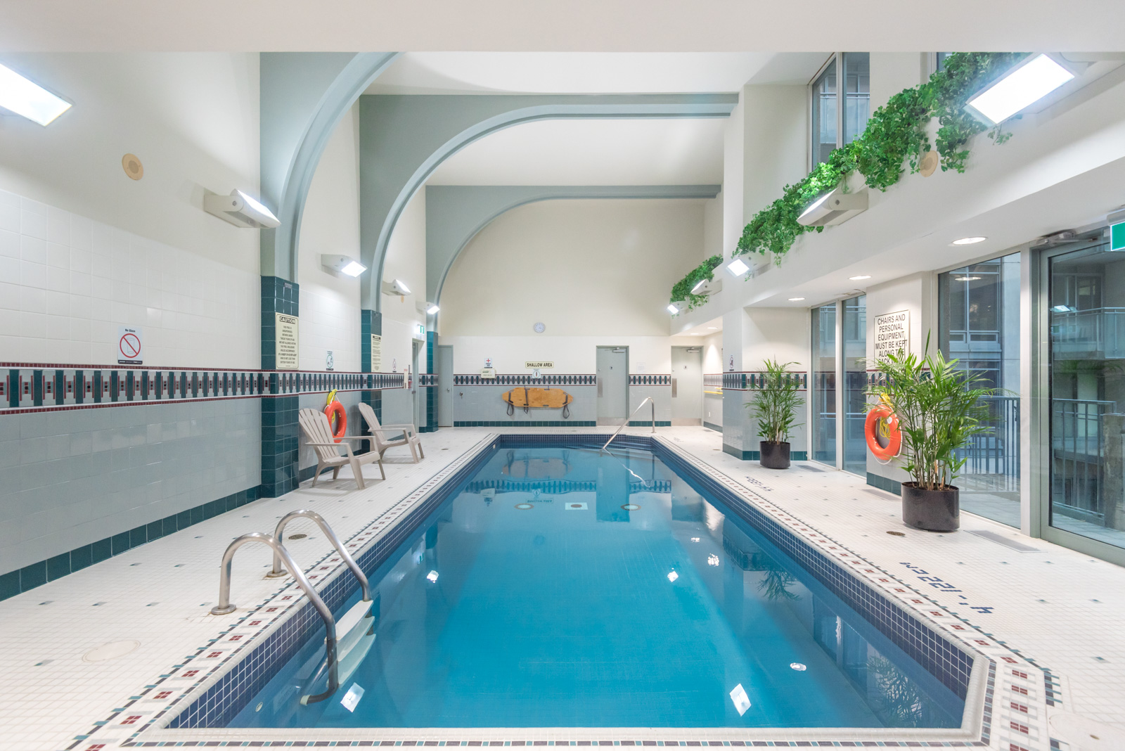 Indoor swimming pool with clear blue water and potted plants at The Metropole.