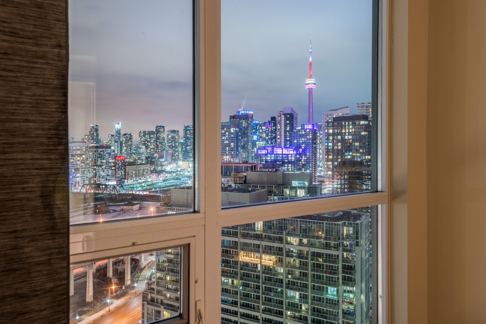 Night view of Toronto, CN Tower and glittering buildings thru bedroom window of 215 Fort York Blvd.