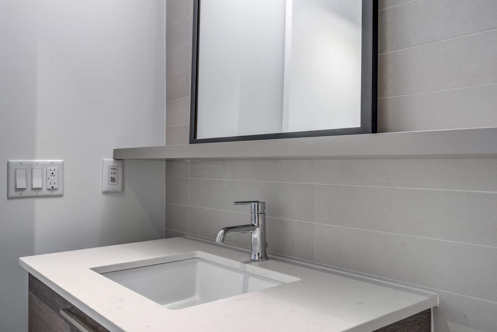 Close up of sink with white counter, shelf and mirror.