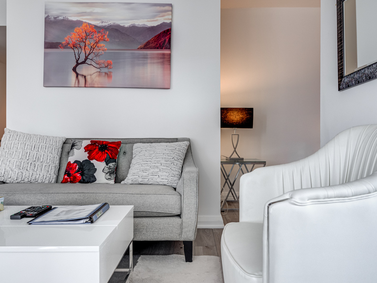 View of 155 Yorkville Ave Unit 1614 living room with gray furniture and colourful pillow and painting.