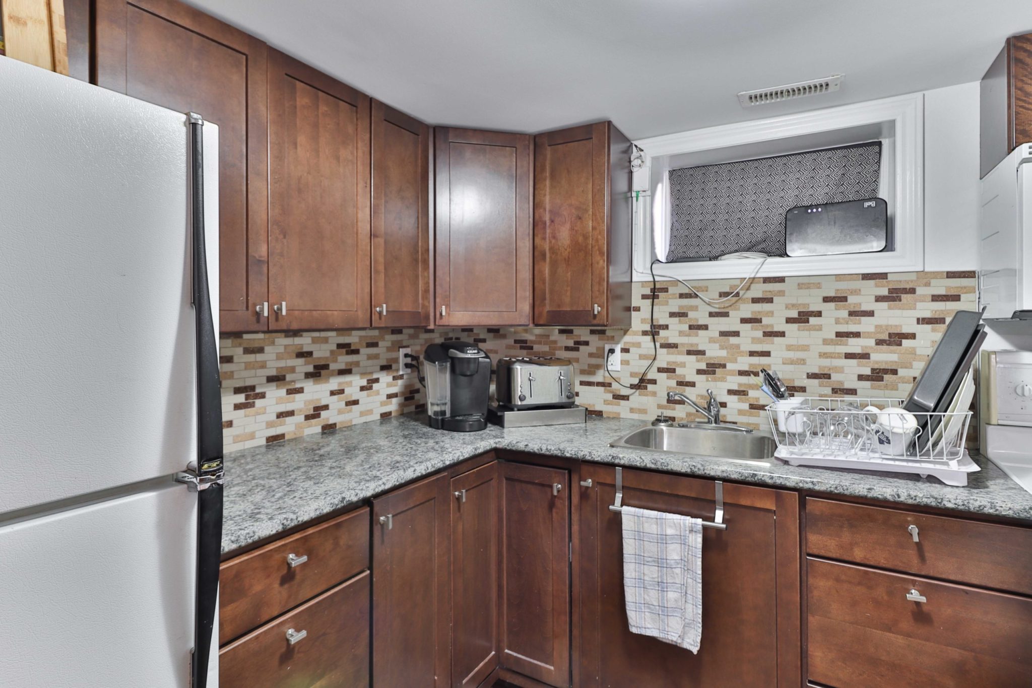 Basement kitchen with lots of wall-mounted cabinets and long counter.