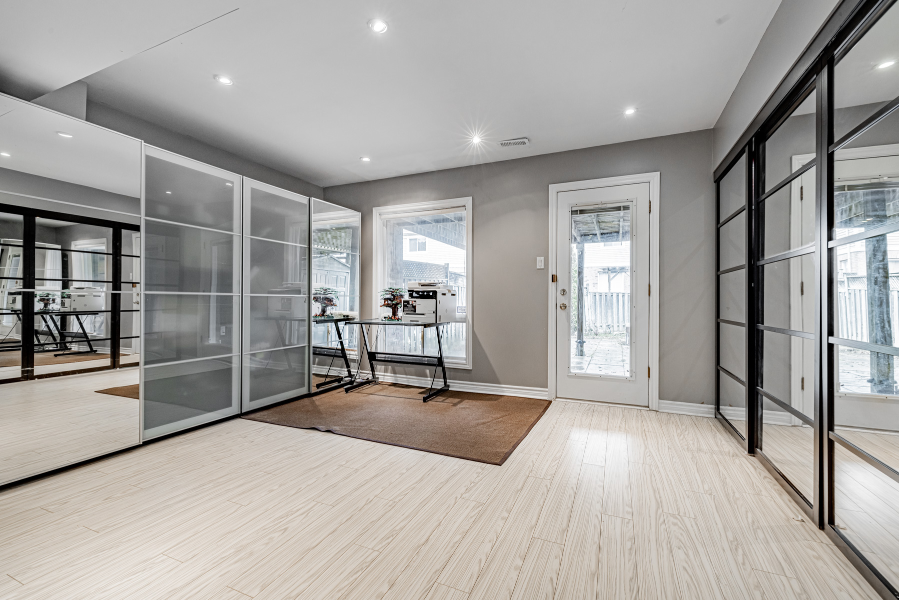 Basement with built-in shelves, laminate floors, large window, sliding glass doors and pot-lights.