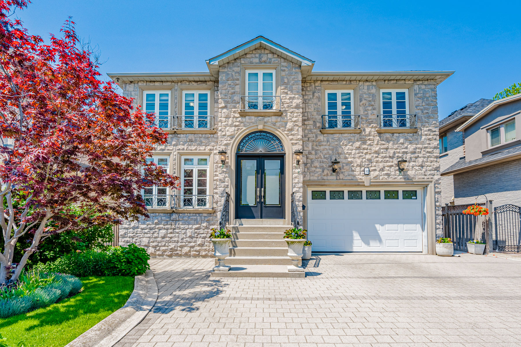 12 Highland Hill gray stone exterior with paved driveway and 2 car garage.