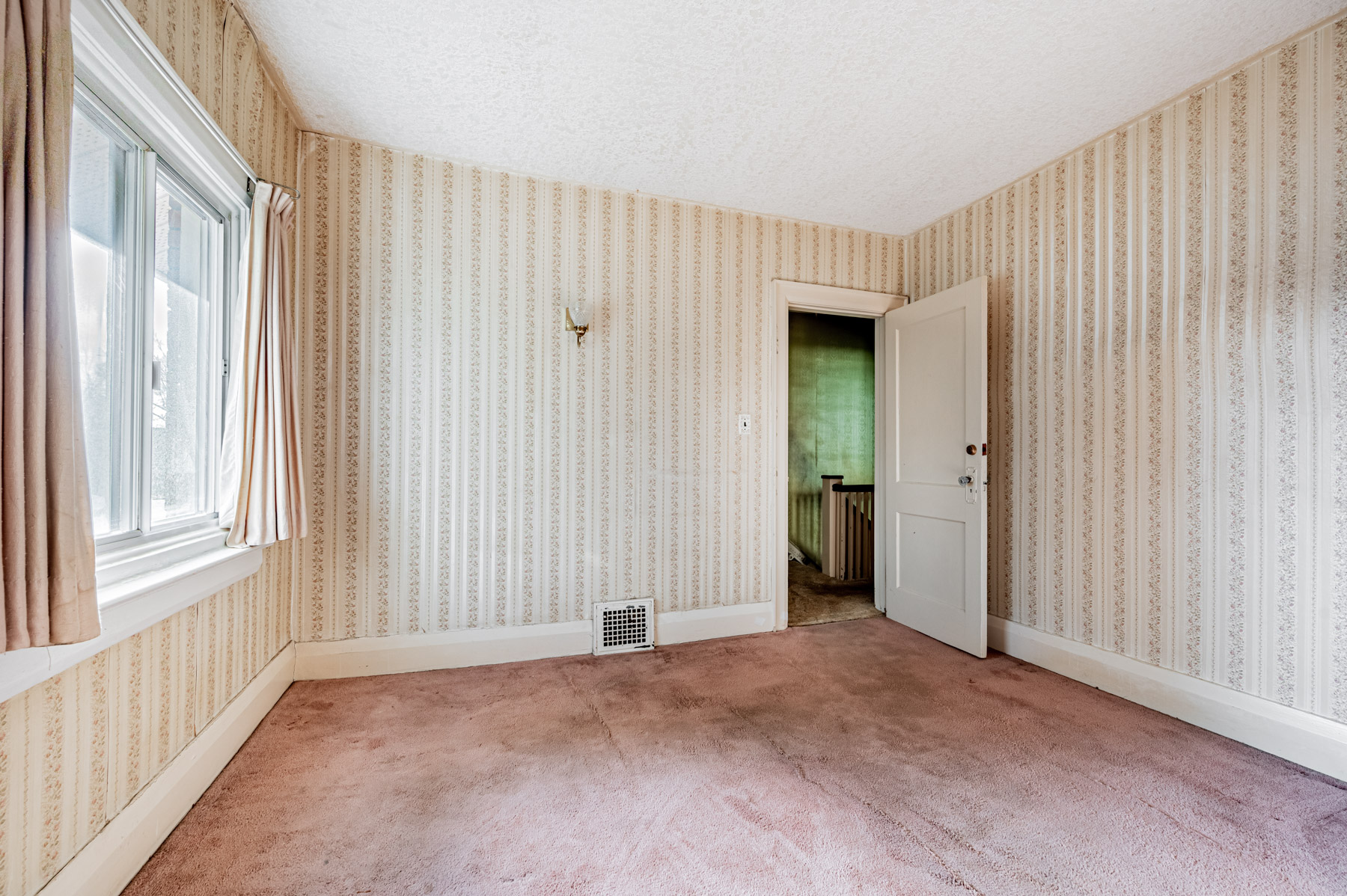 Bedroom with wall-mounted light-fixture, window and broadloom floors.