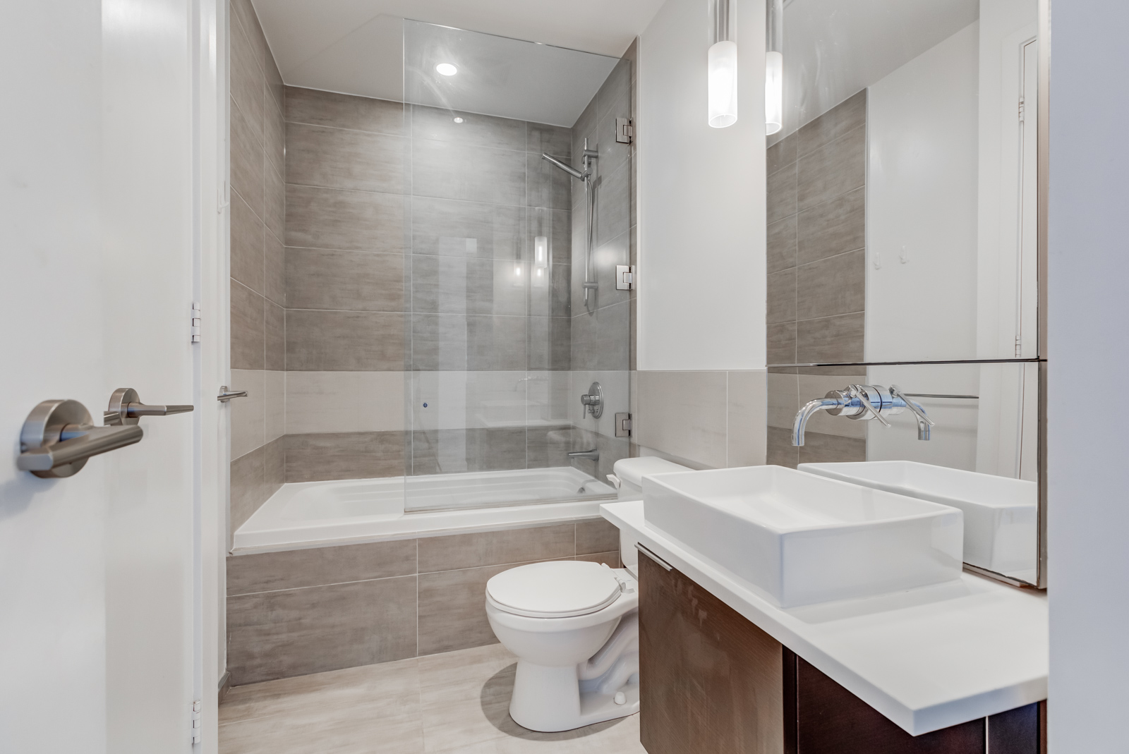 Master bathroom with modern bathtub, raised sink basin, tall mirror, detachable showerhead and brown colours.