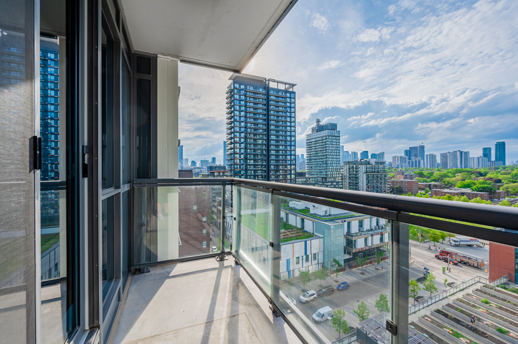 Balcony with glass panels showing streets and cars below.