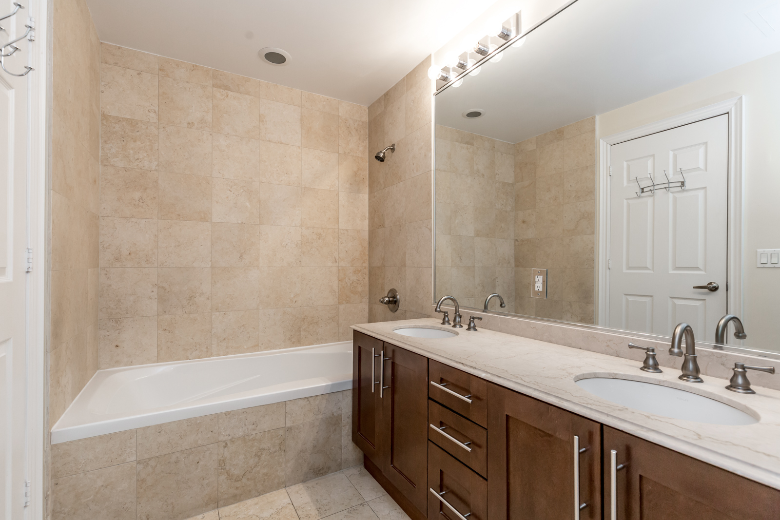 Photo of master bathroom with large mirror, 2 sinks, and bathtub.