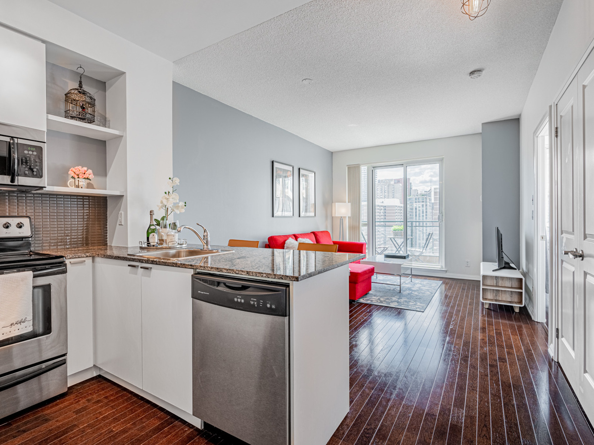 Condo with dark hardwood floors glowing under sunlight.