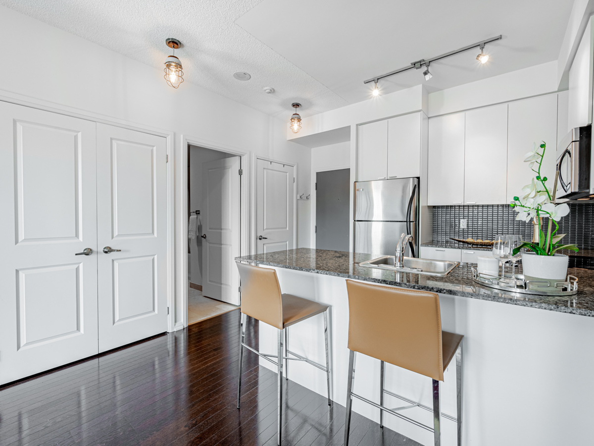 Condo kitchen with track-lights and ceiling lamps.